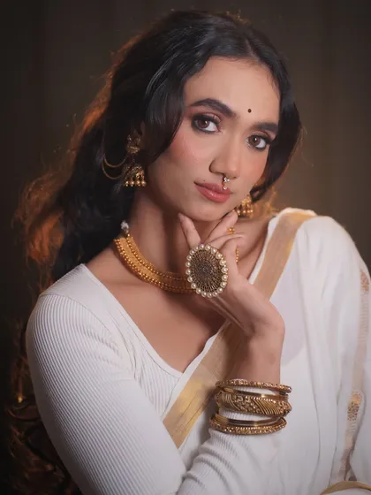 A classic portrait showcasing the complete Onam look, from the delicate bindi to the traditional gold jewelry.