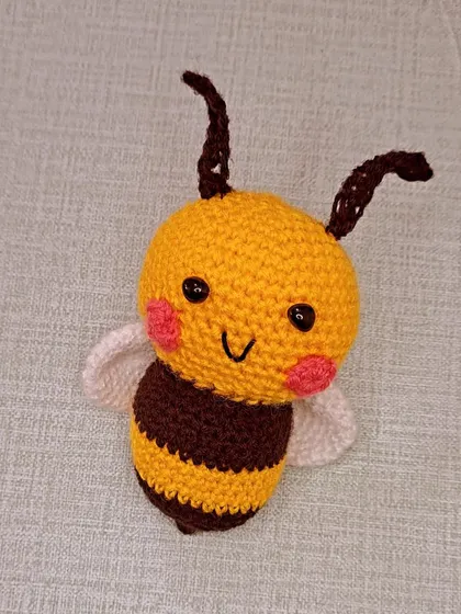 A happy little honeybee with blushing cheeks and tiny wings.