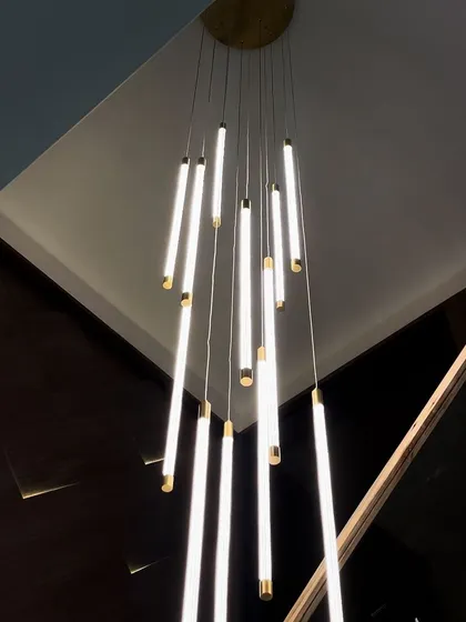 Our height-adjustable Wand Chandelier brings customizable brilliance to any space. This installation in a modern home demonstrates how the fixture can be adapted to create a dramatic, cascading effect over a staircase, making it a true centerpiece.