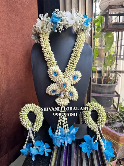 A beautiful floral jewellery set for a baby girl's special day. This set, made with Tagar buds and blue orchids, includes a tiara, necklace, and matching handcuffs.