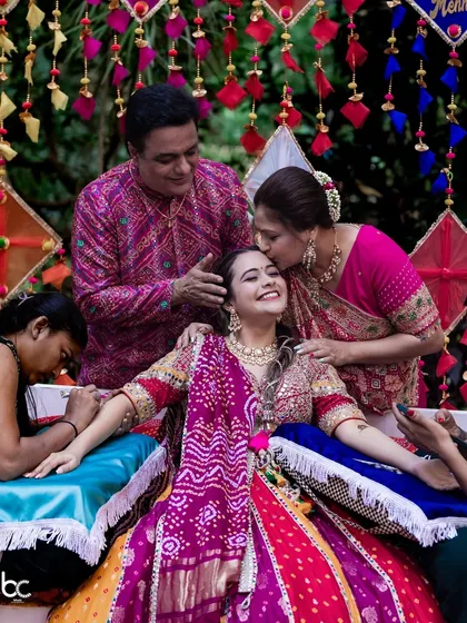 A heartwarming photo of the bride being showered with love and kisses from her parents during her Mehendi ceremony.