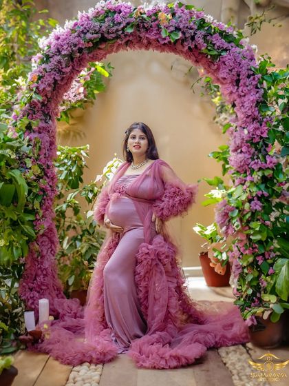 A regal portrait of the mother-to-be under a full arch of pink flowers. The voluminous ruffled gown makes this a truly show-stopping image.