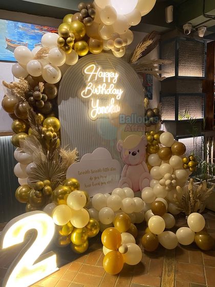 A wider view of the teddy bear birthday setup, showing the full balloon arch with pampas grass details and a custom message board.