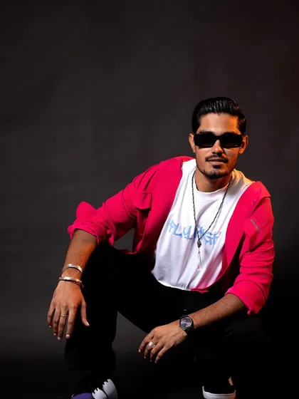 A squatting pose that gives off a cool, urban vibe. The combination of the bright pink shirt and dark background makes the color pop.