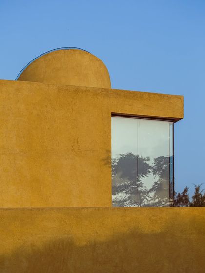 A large window reflects the surrounding trees, making the forest an integral part of the building's facade.