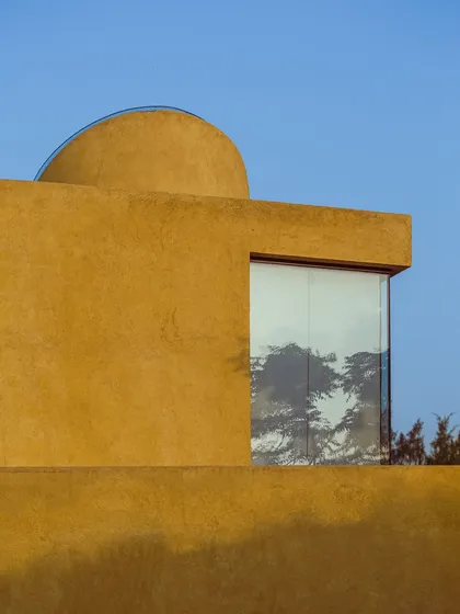 A large window reflects the surrounding trees, making the forest an integral part of the building's facade.
