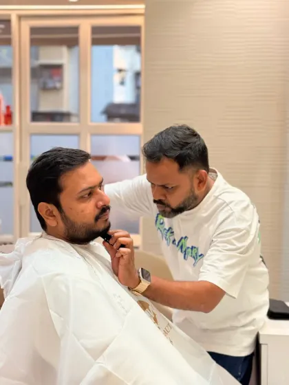 This shot captures the focused interaction between client and stylist during a beard trim, a signature part of our men's grooming experience.