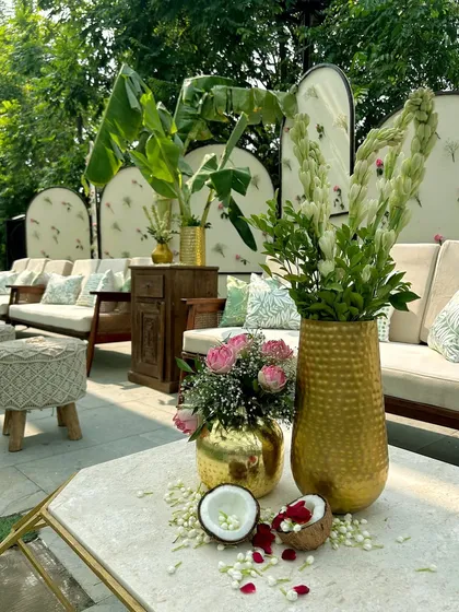A detail shot showing brass vases with tuberoses and roses, alongside fresh coconuts, capturing the authentic essence of a South Indian celebration.