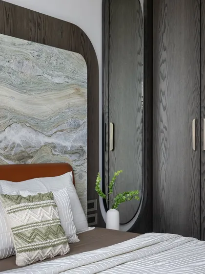 A different angle of the bedroom with the stone and wood headboard, showing how the textures are layered to create a cozy and stylish space.