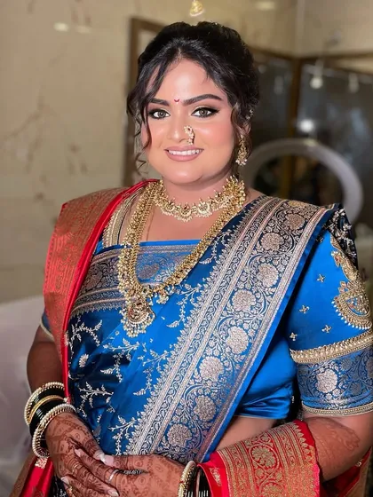 My bride Divya, glowing for her Maharashtrian engagement. We created two traditional looks for her, one in a stunning royal blue saree and another in a beautiful orange one, both featuring classic bold eyes and radiant skin.