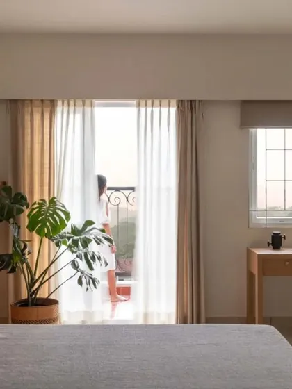 The master bedroom is a serene retreat with a custom headboard combining wood paneling and a deep green upholstered section. The room opens to a balcony, filling the space with light.