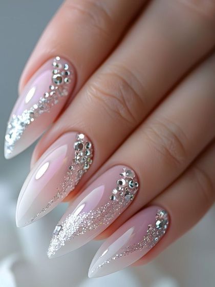 Nail inspiration showing a dramatic ombré stiletto set with scattered glitter and heavy rhinestone embellishments.