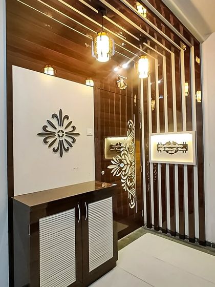 This entryway design features a glossy, dark wood shoe cabinet and a decorative wall partition. The intricate details and integrated lighting create a luxurious and welcoming first impression for the home.