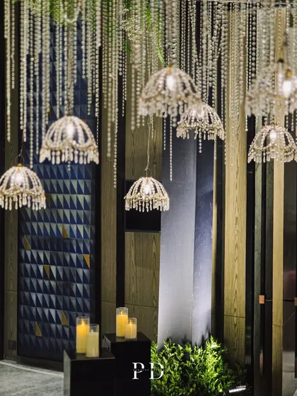 A detail of the hanging crystal chandeliers against a modern, textured wall. This shows how our designs can be adapted to complement the architecture of the venue.