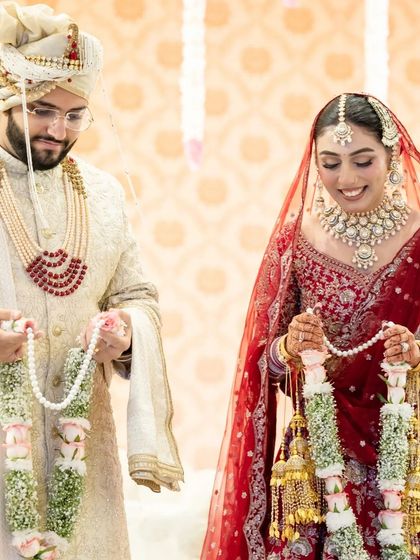 The happy couple holding their garlands after the exchange. This candid photo shows their smiles and the joy of the moment.