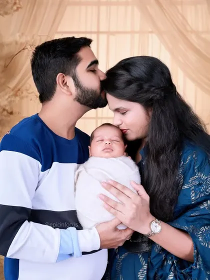 New parents share a kiss over their peacefully swaddled baby. We create a comfortable space for you to express your joy, resulting in natural and heartfelt family photos.
