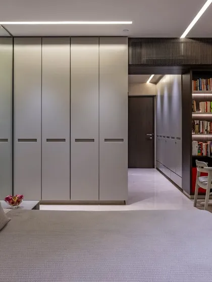 A view from the bed, this image shows the seamless integration of the wardrobe and a compact study nook with a bookshelf. The design maximizes space without sacrificing style.