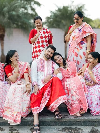 A fun-filled portrait of the Bengali couple with their family, all dressed in beautiful matching sarees.