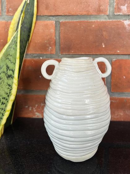 A beautiful, white coiled vase with small loop handles, made by a student. The texture from the coils is left visible as a design element.