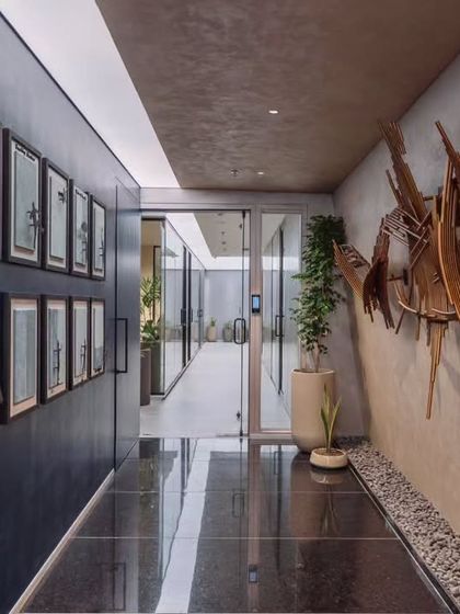 The main hallway is treated as more than just a passage; it's a gallery. Polished black flooring reflects the light, while a feature wall with framed art and a sculptural piece adds a layer of corporate identity and artistic expression.