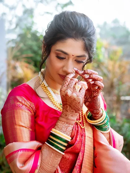 A close-up of the bride adjusting her nath. This shot captures the intricate details of her henna and traditional jewellery.