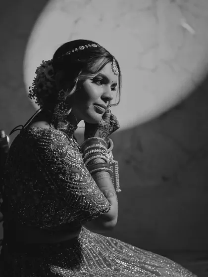 A timeless black and white portrait of the bride, Aneri. The spotlight effect draws all attention to her graceful pose and the intricate details of her wedding attire.