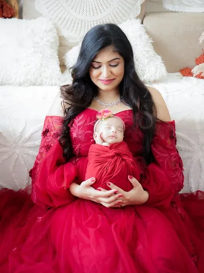 A mother cradling her newborn, wrapped in a stunning red gown that complements the baby's swaddle. Coordinating colors can make a portrait even more striking.