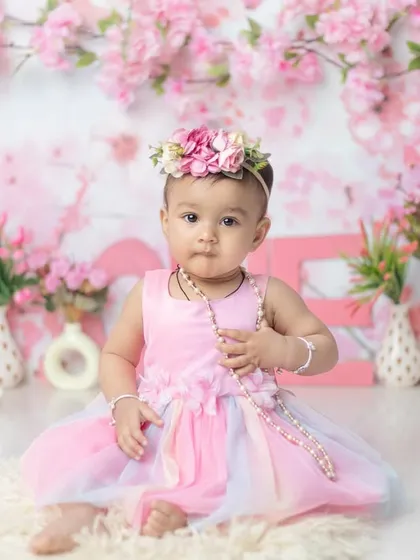 Holding a string of pearls, this little doll looks so elegant in her pink dress and floral crown.