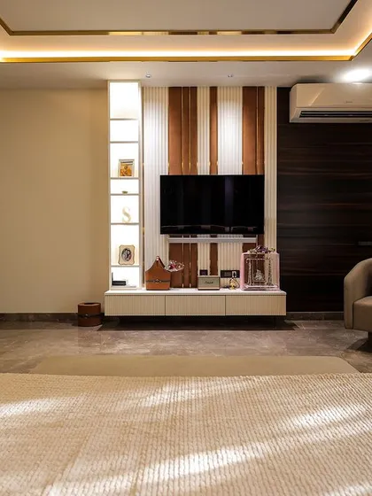 A spacious and serene bedroom with a neutral color palette. The design includes a comfortable seating area and a simple, elegant TV unit, creating a space that is perfect for both rest and relaxation.