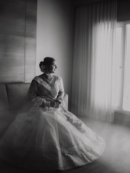 A dreamy and ethereal black and white portrait. The soft, hazy light from the window envelops the bride, creating a beautiful, almost painterly image of her on her wedding day.