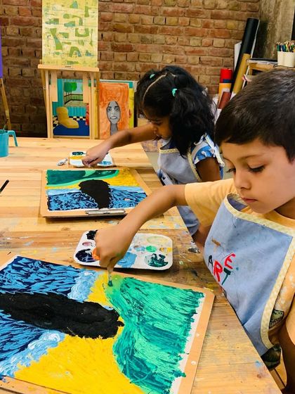 Even our youngest artists can explore the masters. Here, two children are engrossed in their textural Van Gogh paintings.