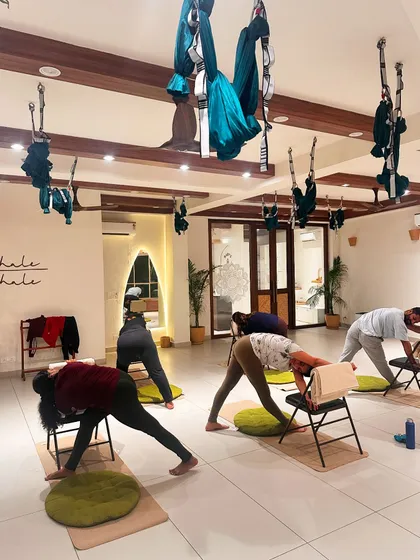 Students use chairs for a supported pyramid pose, allowing for a deep hamstring stretch without straining the back.