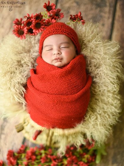 A bold and beautiful choice. The vibrant red knit wrap and matching hat make this newborn portrait stand out, surrounded by delicate red flowers.