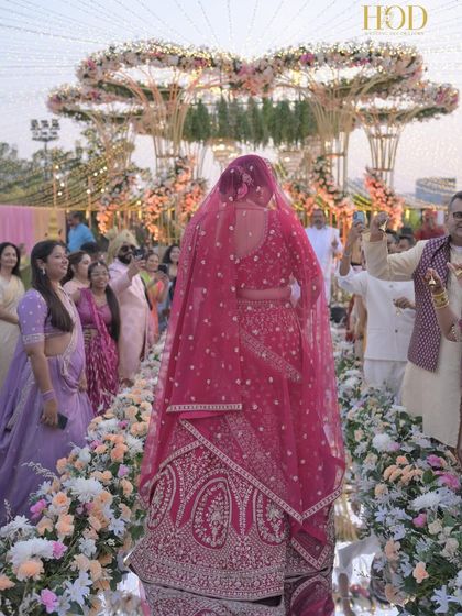 A shot from behind the bride as she walks down the aisle, showing her perspective as she approaches the magnificent floral mandap.