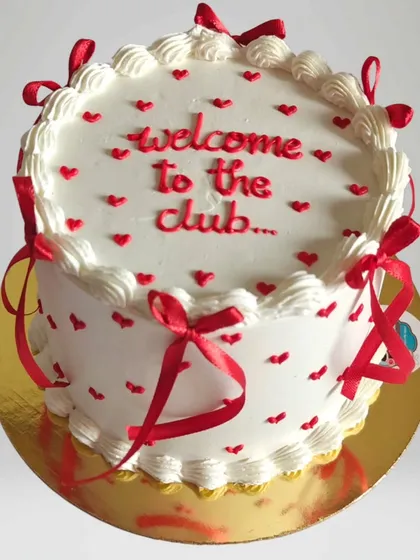 A fun "Welcome to the club" cake with red ribbons and hearts. This design is perfect for celebrating a new job, marriage, or any new life chapter.