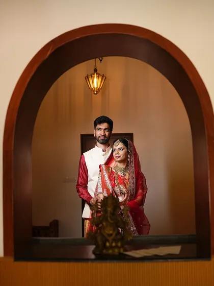 A creatively framed shot of the couple through an archway, adding depth and an artistic touch to their wedding portrait.