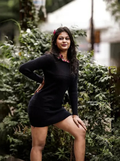 A powerful stance against a green, leafy background, showcasing the simple but effective elegance of a little black dress.
