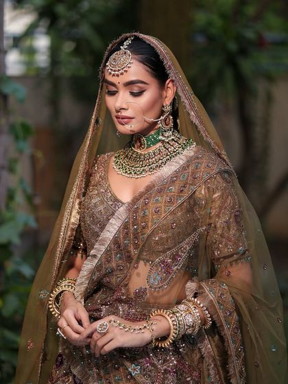 A full view of the bride in her stunning olive-toned lehenga. The makeup is designed to complement the rich colors and intricate embroidery of the outfit.