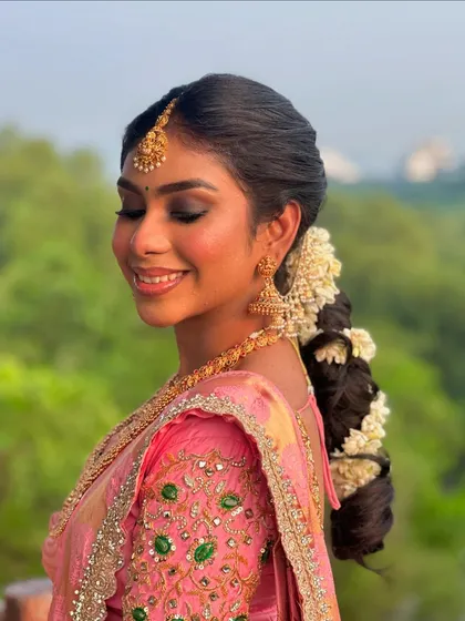 A soft and dreamy profile shot. The focus here is on the flawless eye makeup and the traditional braided hairstyle adorned with fresh flowers.