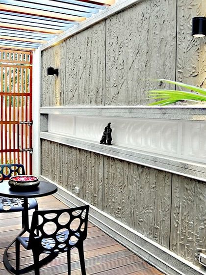 A cozy outdoor seating area with a textured concrete wall featuring a leaf-like pattern. This space demonstrates our attention to detail and our ability to create artistic, functional corners for relaxation.