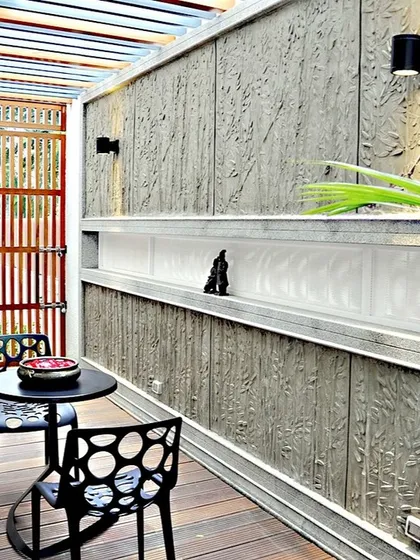 A cozy outdoor seating area with a textured concrete wall featuring a leaf-like pattern. This space demonstrates our attention to detail and our ability to create artistic, functional corners for relaxation.
