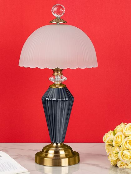 This lamp combines a fluted navy ceramic base with a frosted glass dome shade. The crystal and brass accents add a touch of vintage-inspired glamour to the otherwise modern design.