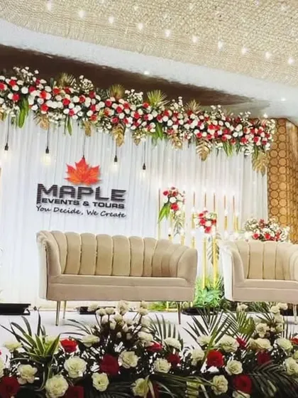 A grand and traditional stage design featuring a rich combination of red and white flowers with golden leaf accents. The three-part seating arrangement provides ample space for family on the big day.