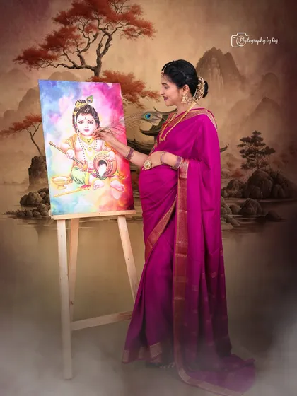 A creative studio portrait of a couple with a painting of Baby Krishna, celebrating their upcoming arrival.