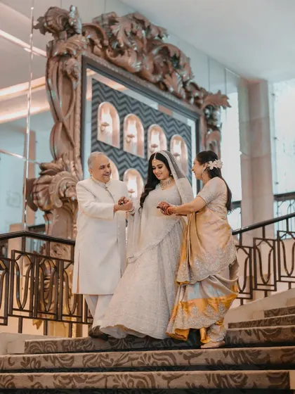 The bride being lovingly escorted down the grand staircase by her parents. A moment of unity, support, and family love.