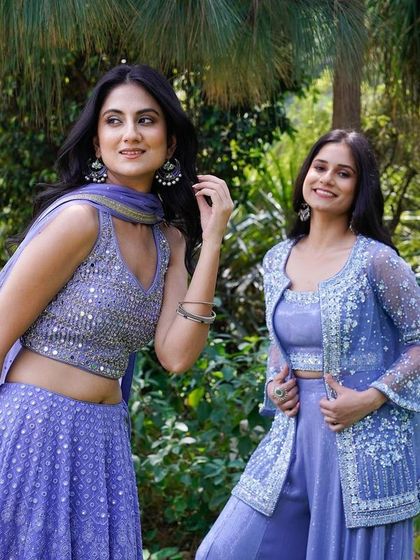 Another beautiful shot from the same series, capturing a different interaction. It showcases the mirror work on the lehenga and the sheer jacket, set against a natural, leafy backdrop.