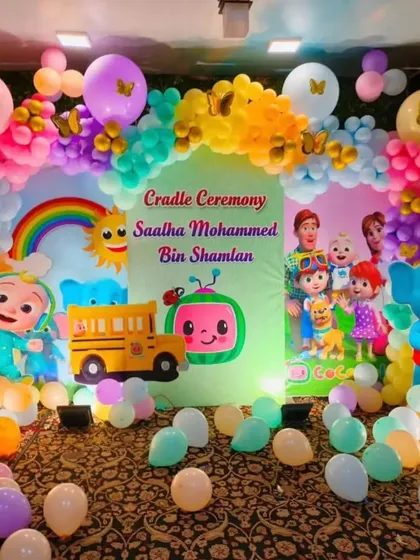A Cocomelon themed cradle ceremony with a colorful backdrop and balloon arch.