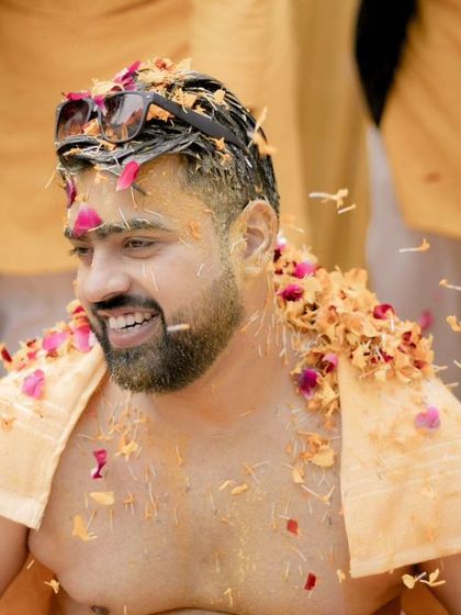 The groom, Akshat, covered in flower petals, his happy and relaxed expression showing he's enjoying every moment.