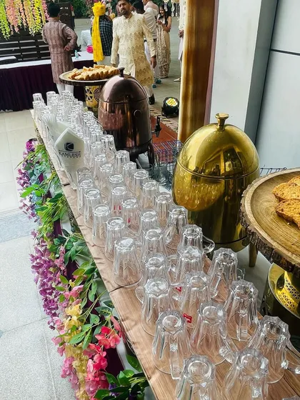 Another view of the tea station, showcasing the neat arrangement of glasses, traditional copper and brass urns, and fresh cookies. It's a welcome corner at any time during an event.