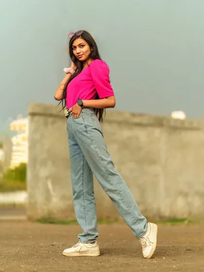 A full-body shot from the side, showcasing the relaxed fit of the jeans and the bright color of the top.